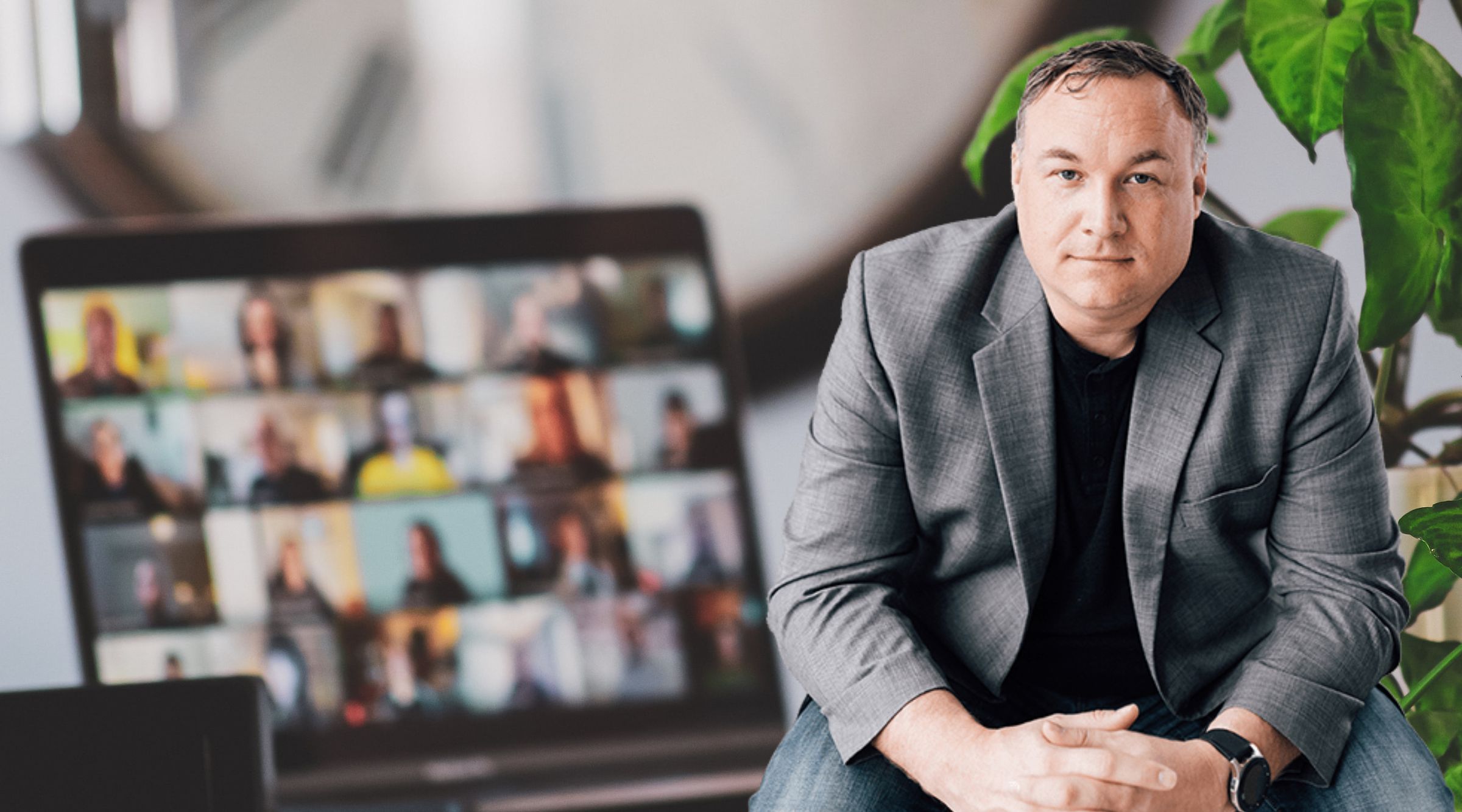 Jimmy Kelley with a laptop in the background that has an online meeting on the screen