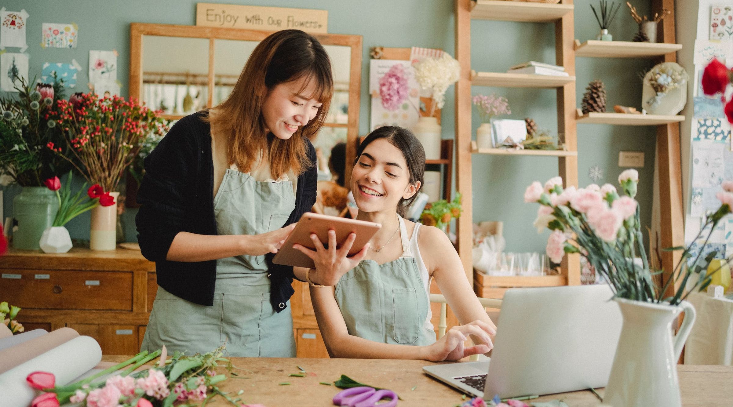 Two florist woman looking at a an tablet and smilling