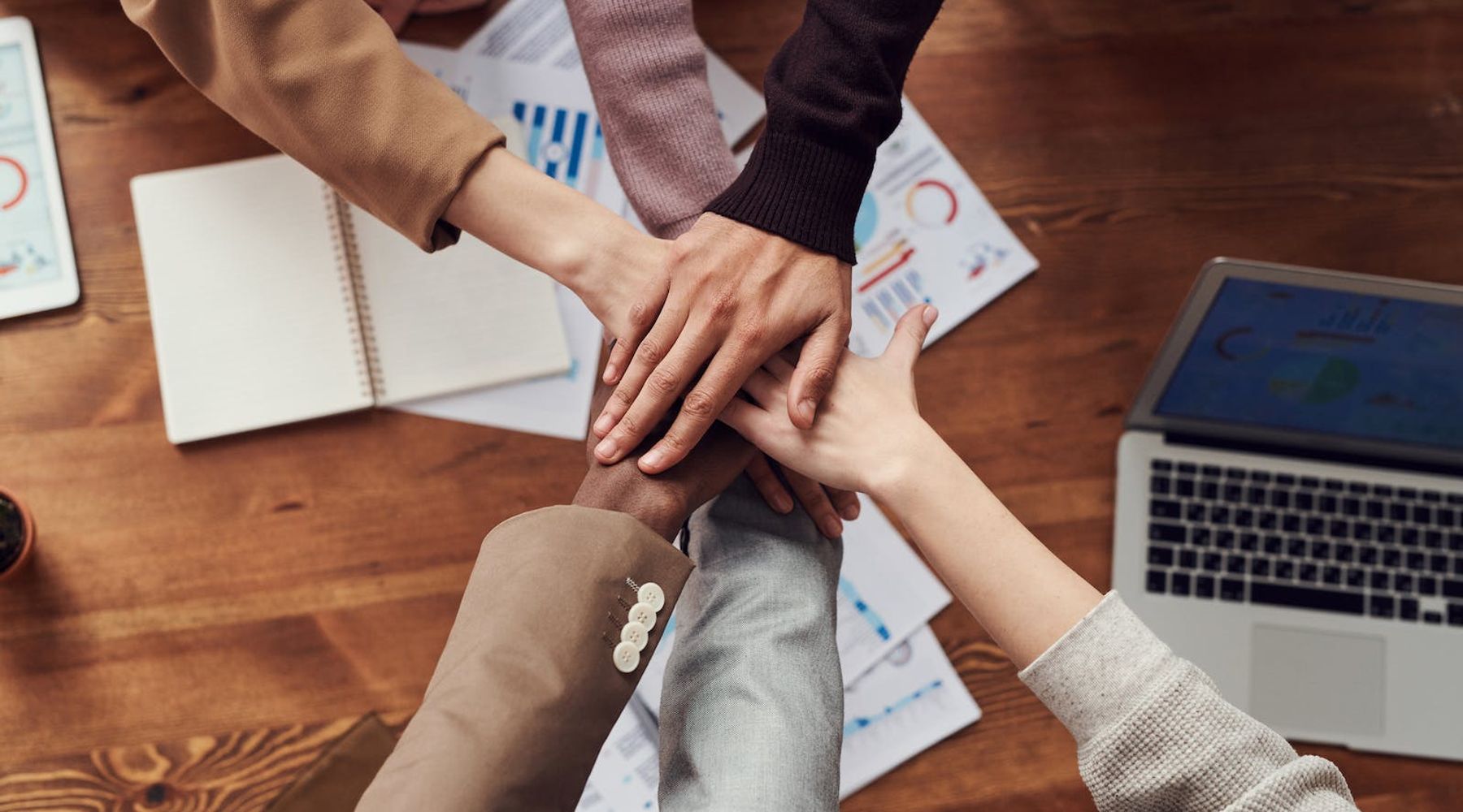 People putting there hands together above a table