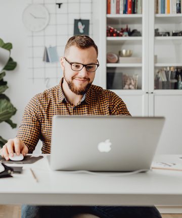 A man looking at his laptop on a desk